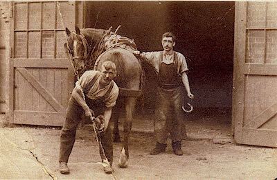 Two farriers shoeing a horse, 1930s sepia photograph